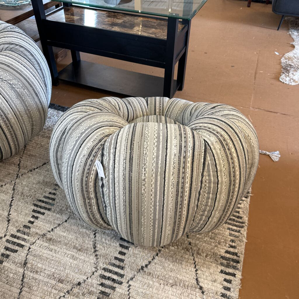 Striped ottoman on a patterned rug with a cardboard box in the background