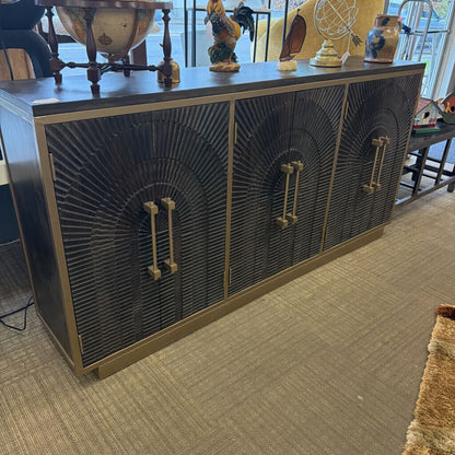 Decorative sideboard with intricate design and gold handles in a room setting.