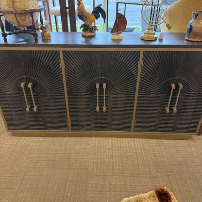 Decorative sideboard with sunburst pattern and various small decorative items on top.