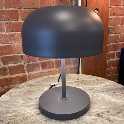 Black table lamp on a marble surface with a brick wall background