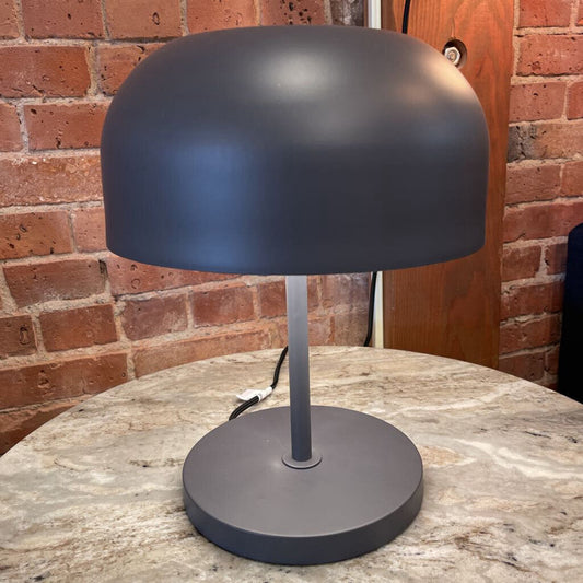 Black table lamp on a marble surface with a brick wall background