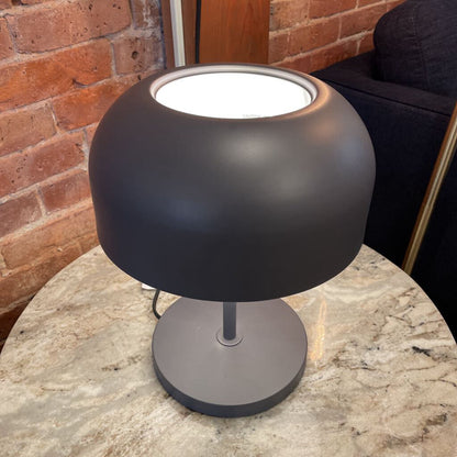 Black table lamp on a marble surface with a brick wall background