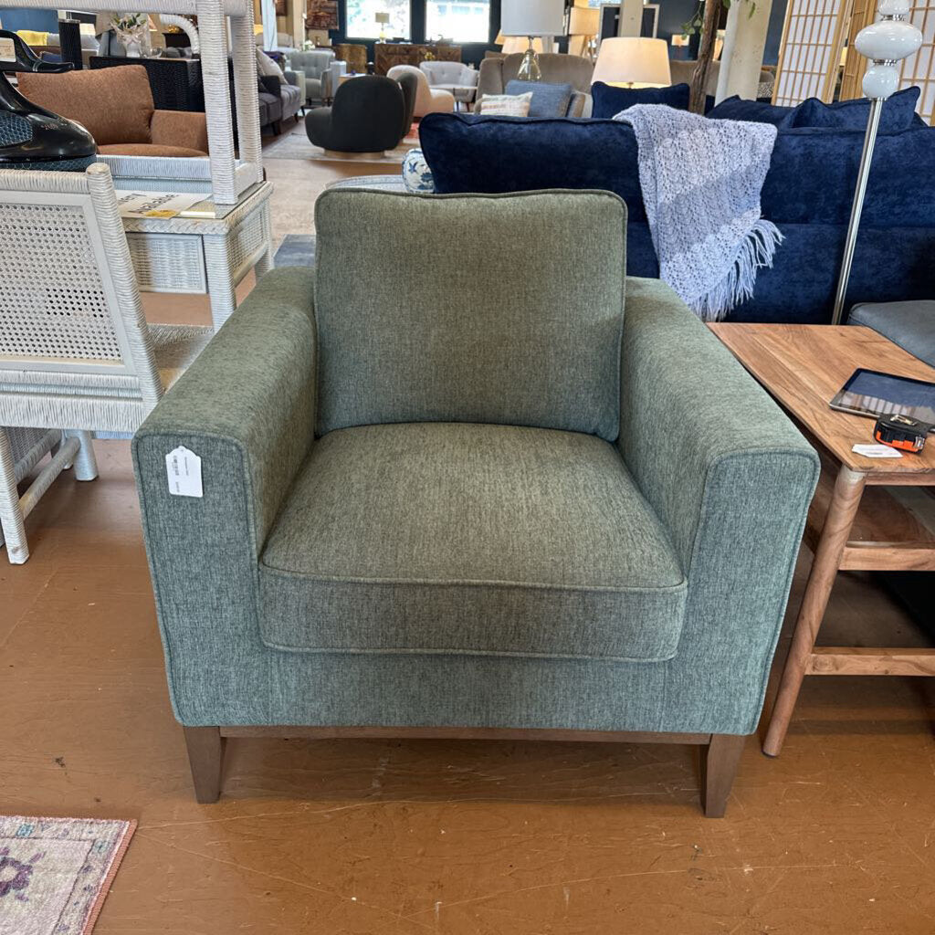 Green armchair in a furniture store setting with other items in the background
