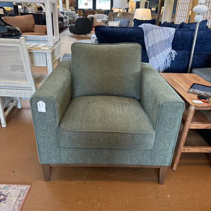 Green armchair in a furniture store setting with other items in the background