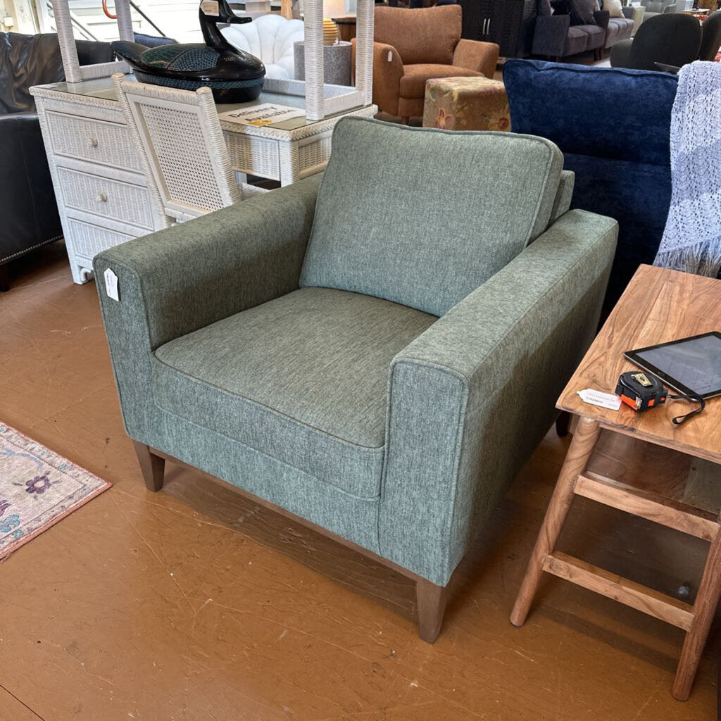 Gray armchair in a room with furniture and decor items.