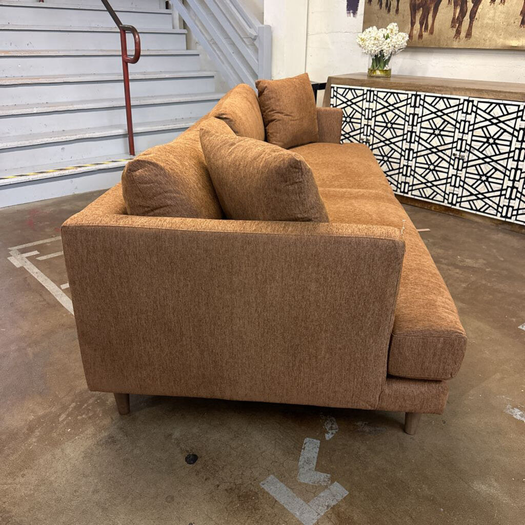 Brown sofa in a room with a staircase and decorative elements.