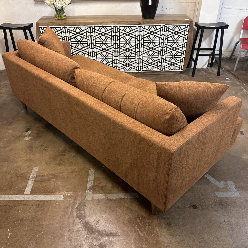 Brown sofa in a room with a decorative cabinet and stools.