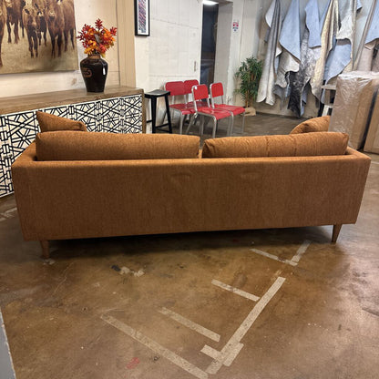 Brown sofa in a room with red chairs and a patterned wall.