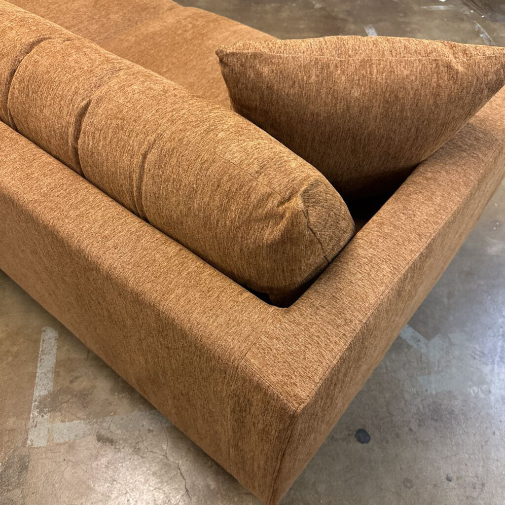 Brown textured sofa with a pillow on a concrete floor