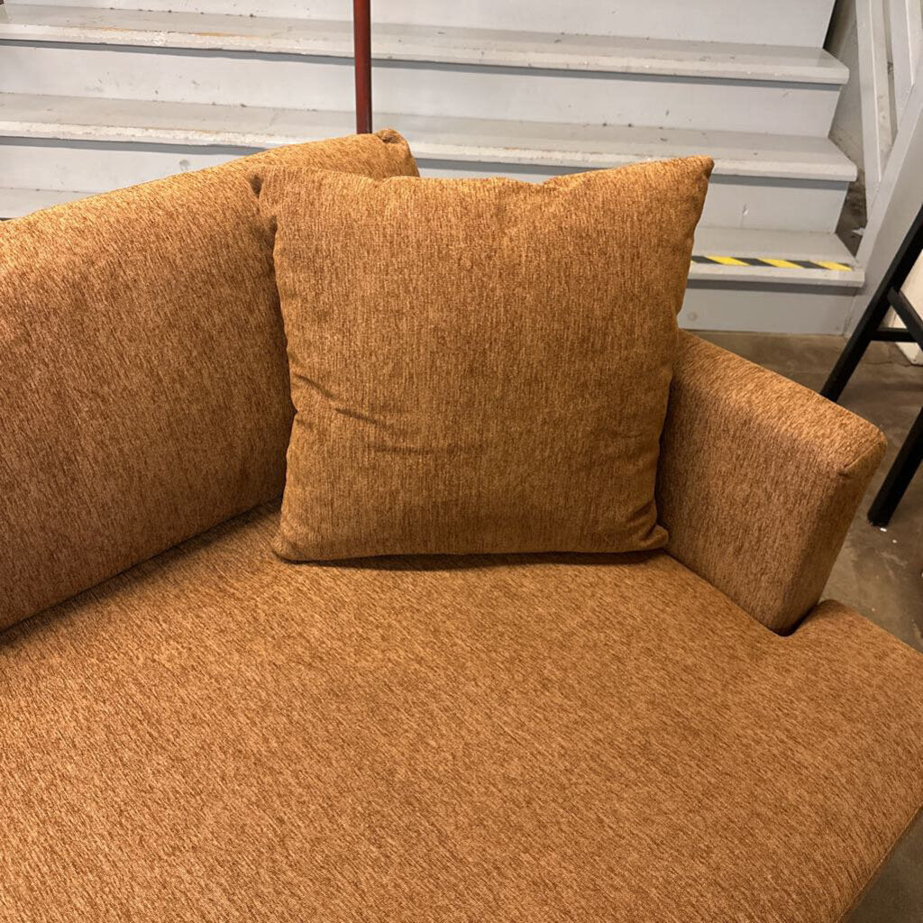 Brown textured sofa with a pillow against a neutral background