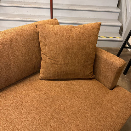 Brown textured sofa with a pillow against a neutral background