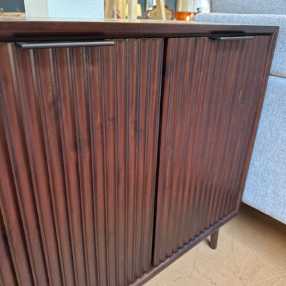 Wooden cabinet with ribbed design in a room setting