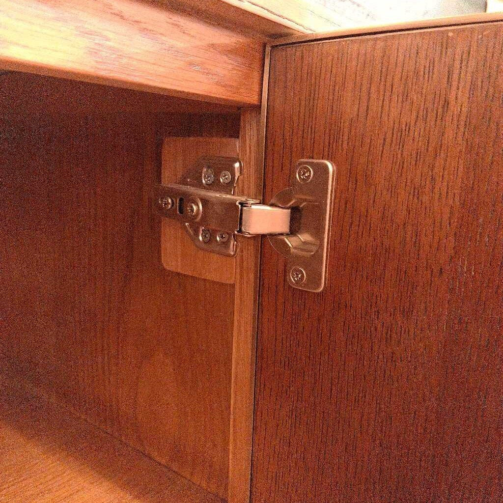 Close-up of a wooden cabinet with a metal hinge