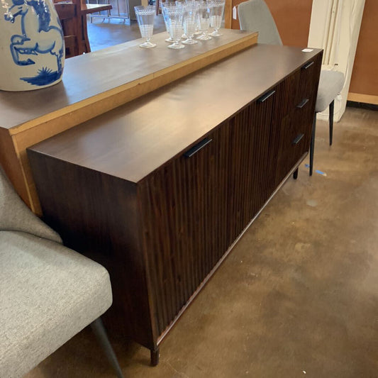 Dark wood sideboard with a light wood countertop in a room setting.