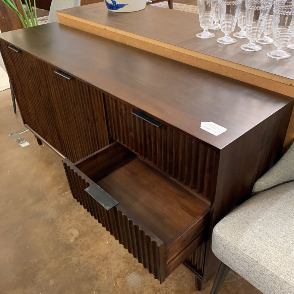Wooden sideboard with open drawer in a room setting