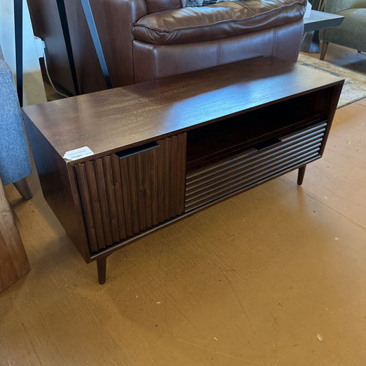 Wooden console table on a wooden floor with a brown leather chair in the background.