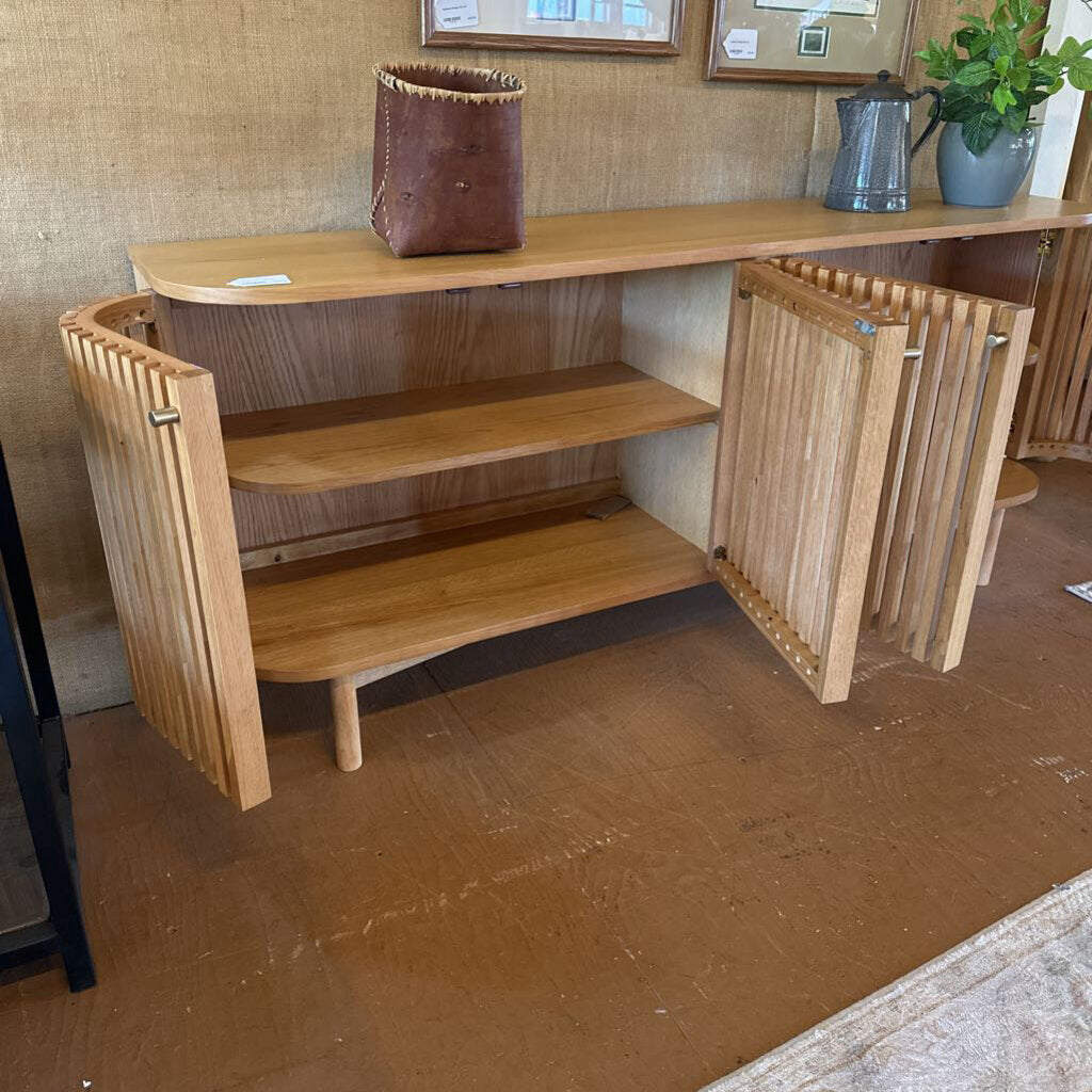 Wooden shelf unit with a plant and decorative items on a brown floor.