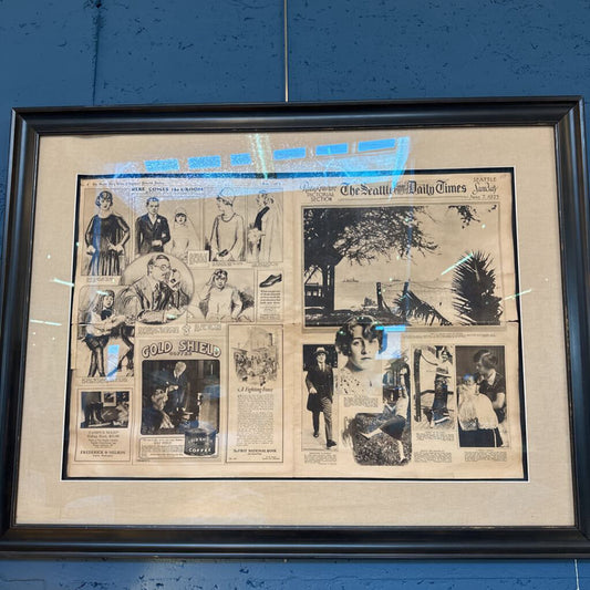 Framed collage of vintage newspaper clippings on a blue wall