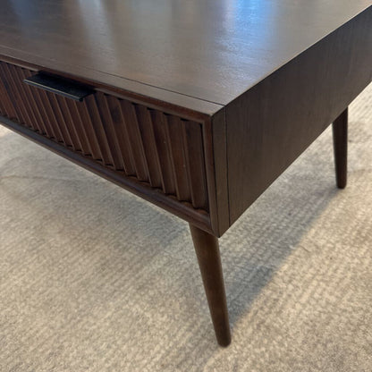 Wooden desk with a single drawer on a carpeted floor