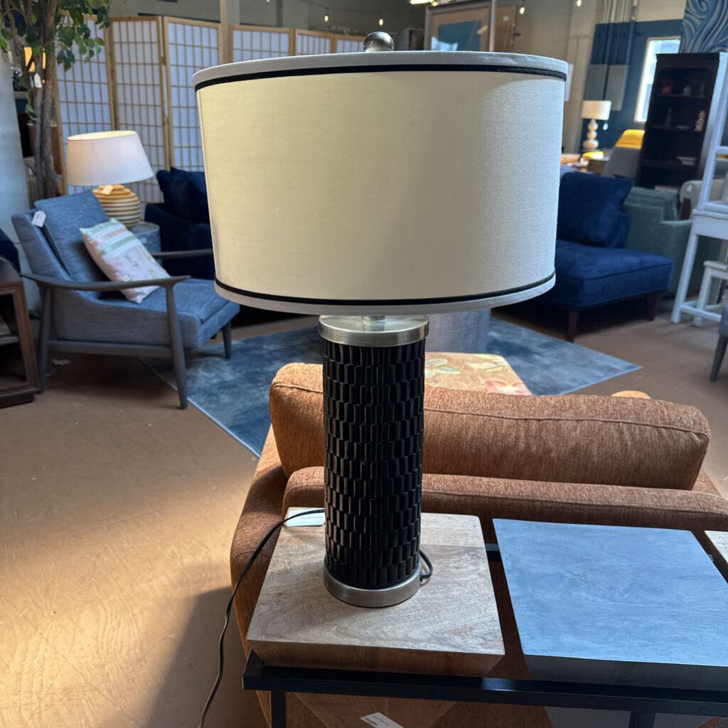 Lamp with beige shade and black base on a table in a living room setting