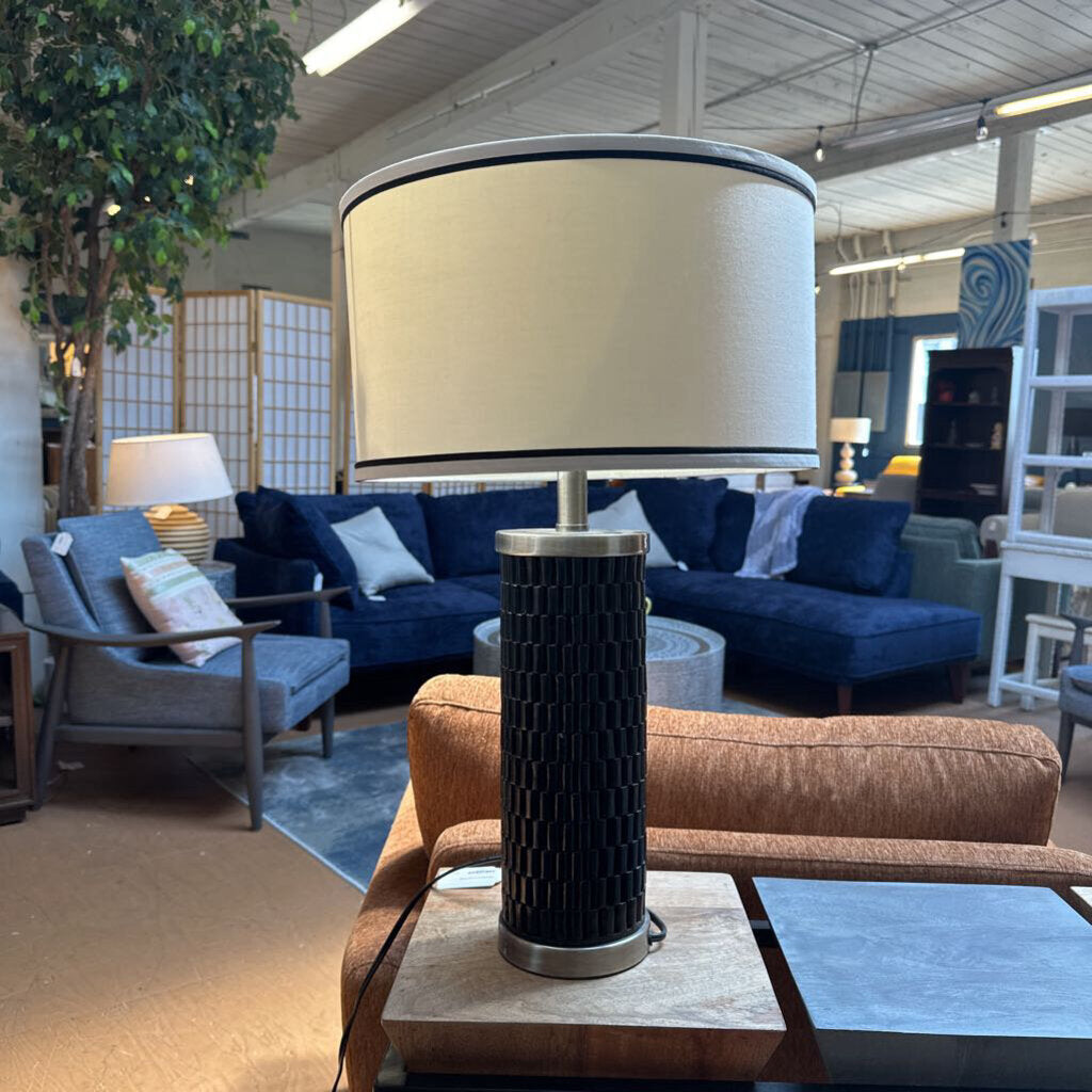 Lamp with a beige shade and black base in a living room setting