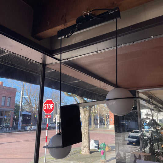 Pendant lights hanging from the ceiling with a view of a street outside a store window.