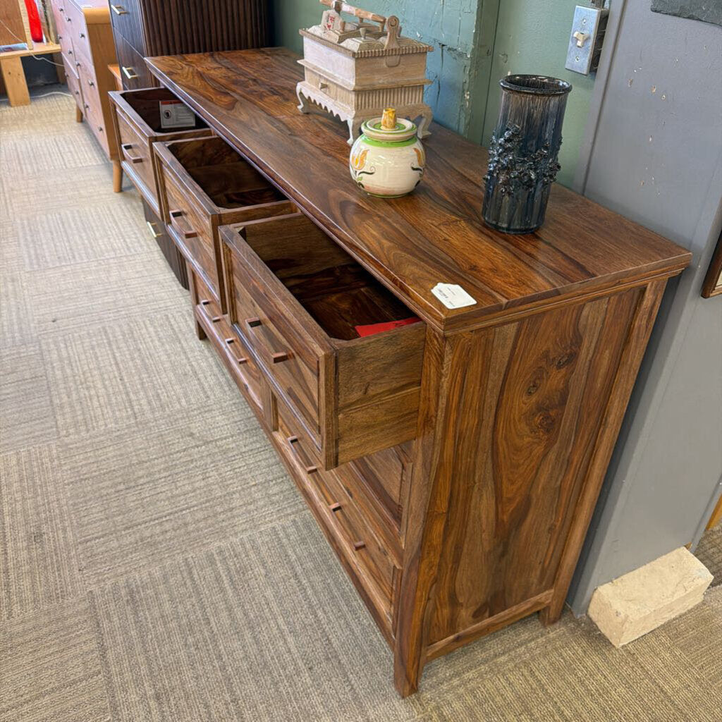 Wooden sideboard with drawers and decorative items in a room setting.