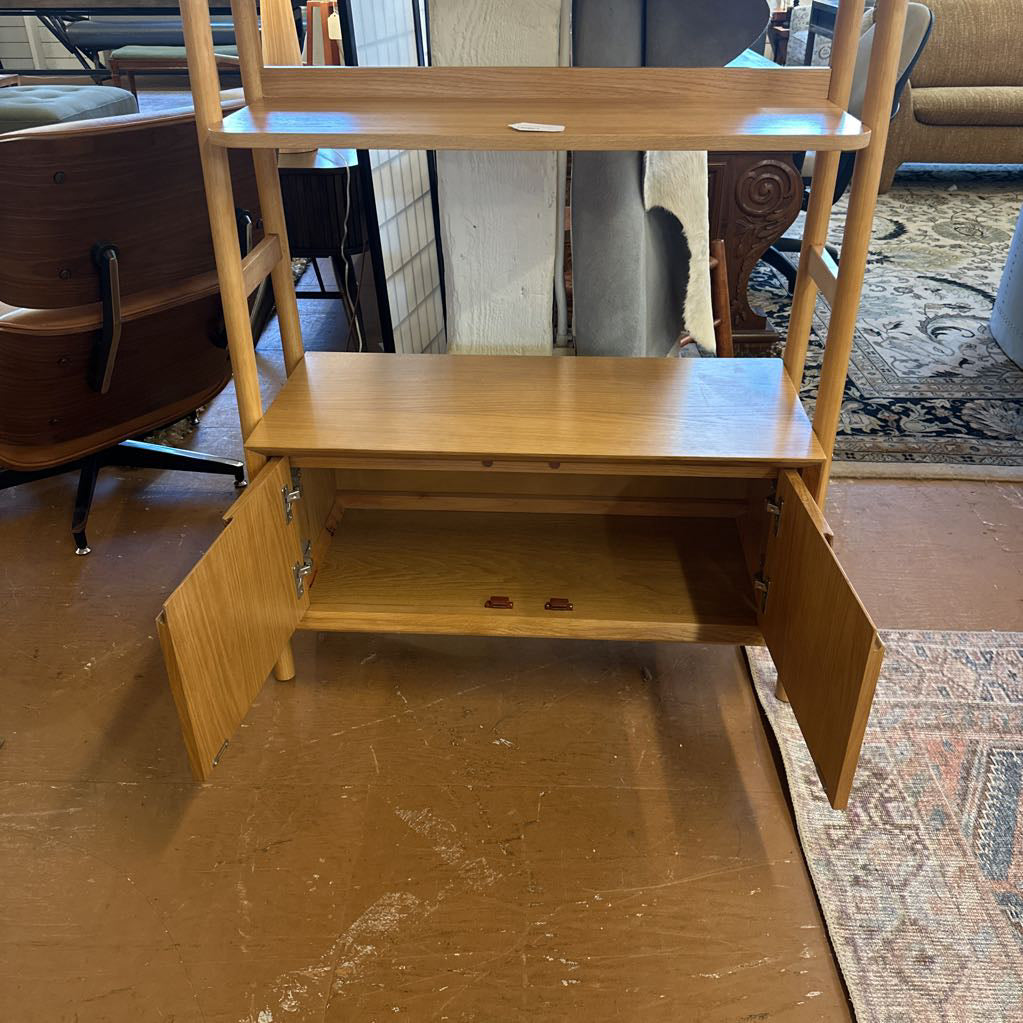 Wooden bookshelf with one door open in a room setting