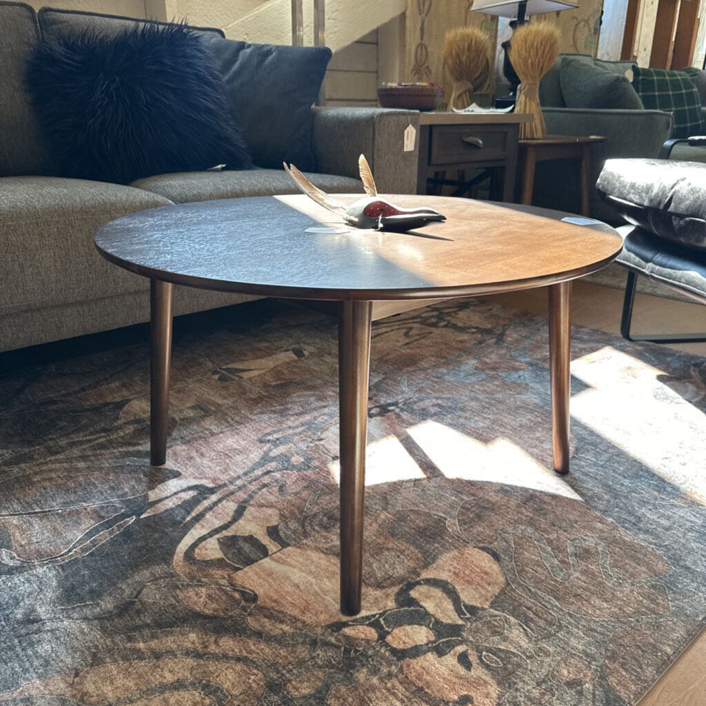 Round wooden coffee table in a living room setting with furniture and decor.