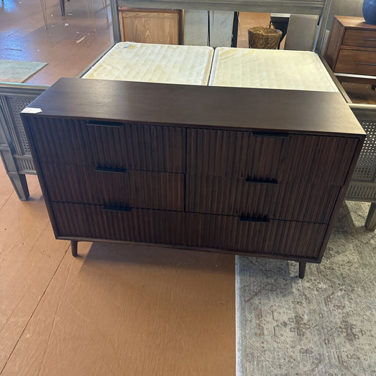 Dark wood dresser with three drawers on a wooden floor.