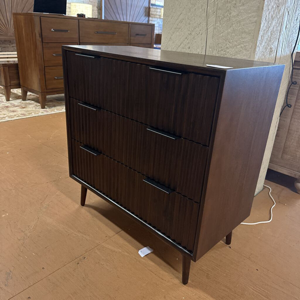 Wooden dresser with multiple drawers on a wooden floor.