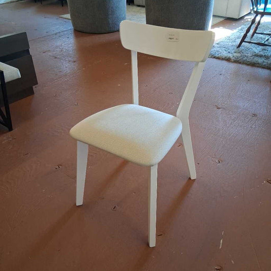 White chair with beige cushion on a wooden floor