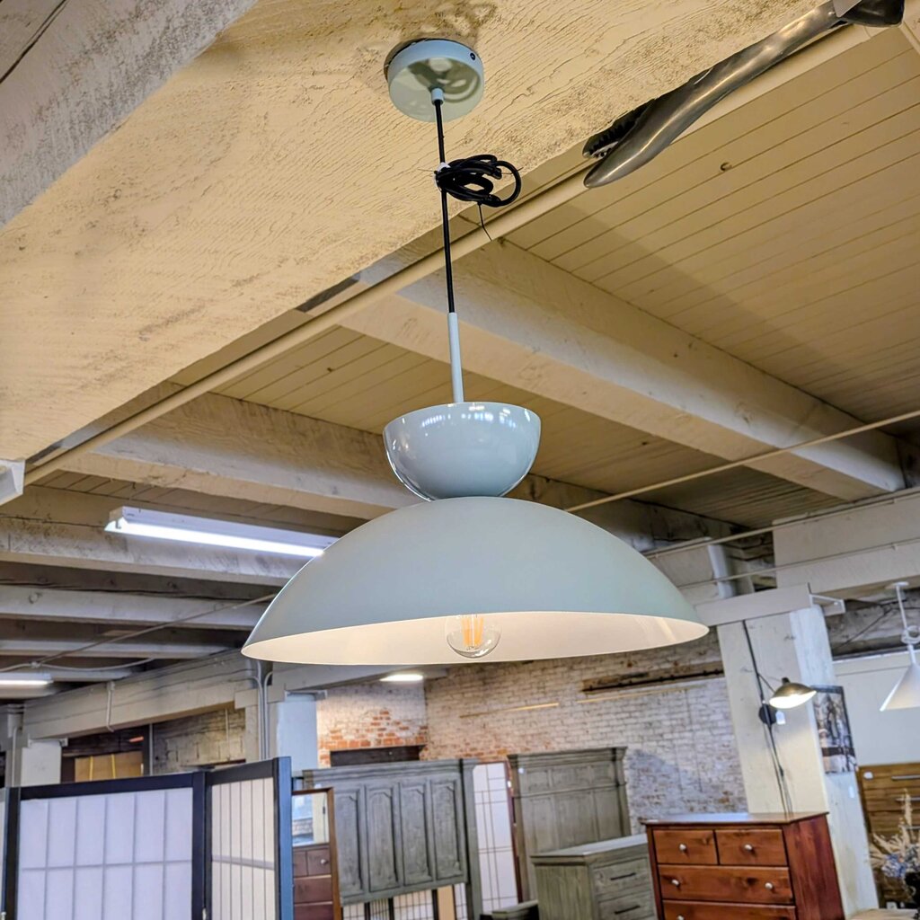 Light blue pendant lamp hanging from a ceiling in an indoor setting with wooden beams and furniture.