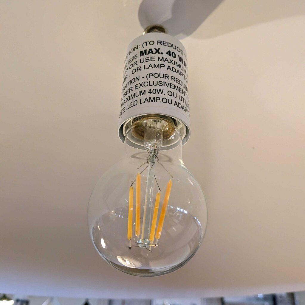 Clear LED light bulb with visible filaments against a neutral background