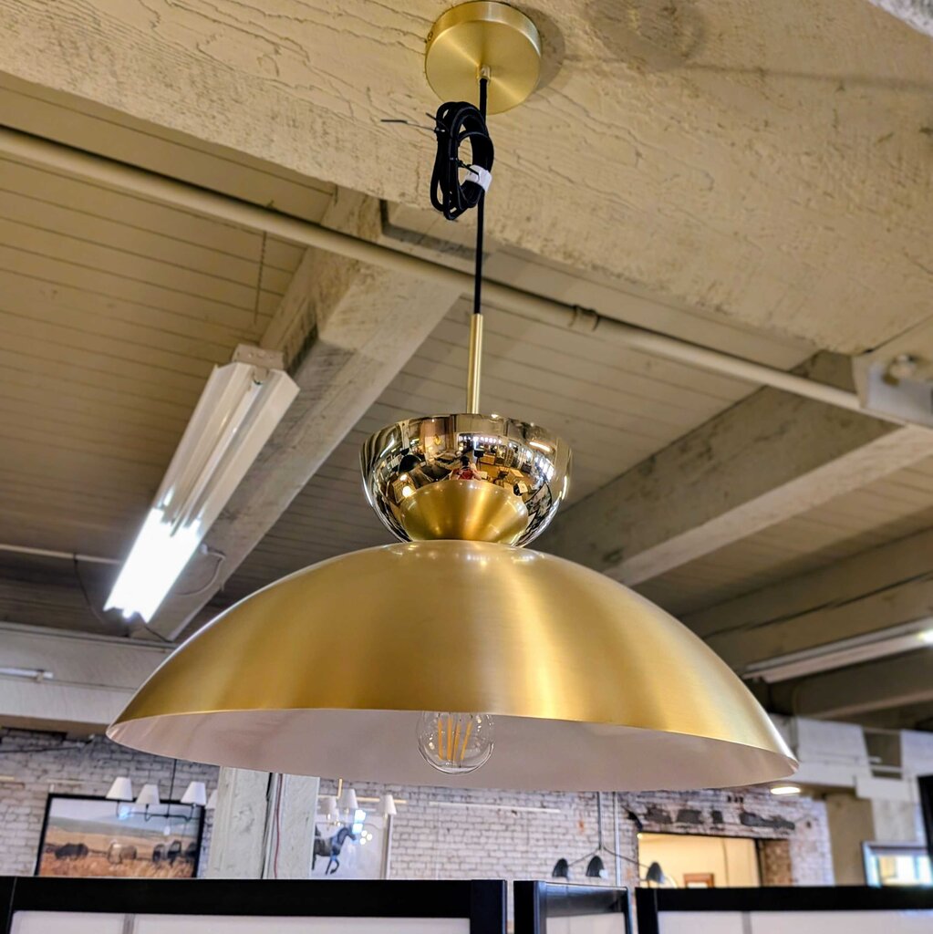 Gold pendant light hanging from a ceiling with a rustic interior background