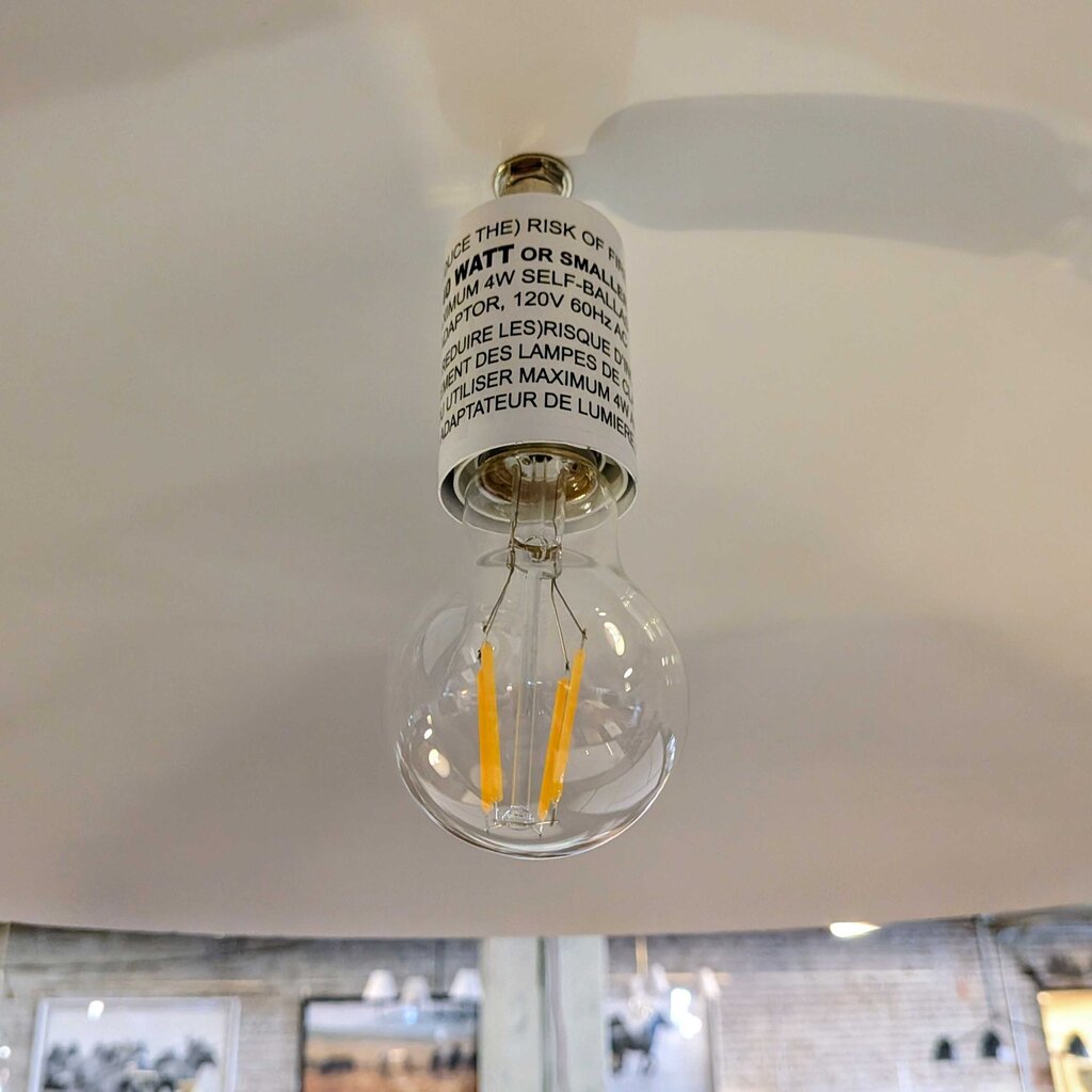 Clear light bulb with visible label on a white ceiling