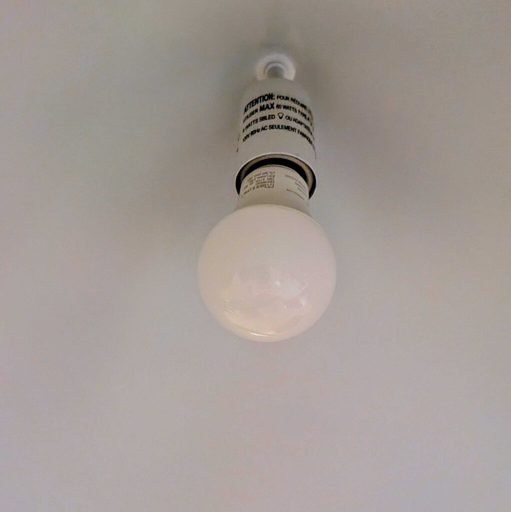 Light bulb hanging from a ceiling with a white background