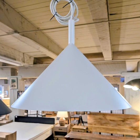 White pendant light hanging in a room with wooden beams and furniture.