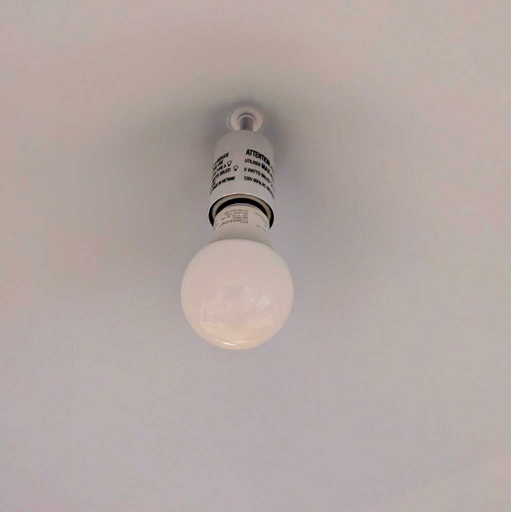 Light bulb hanging from a ceiling with a neutral background