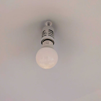 Light bulb hanging from a ceiling with a neutral background