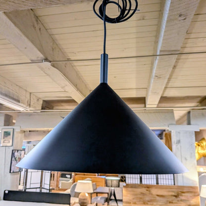 Black pendant light hanging from a wooden ceiling