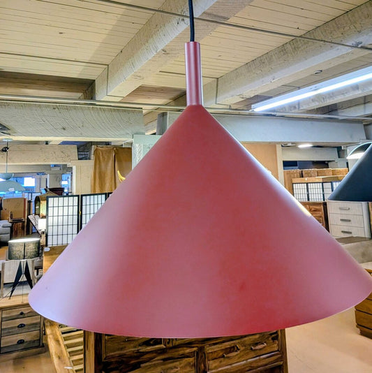 Pink pendant lamp hanging in a room with wooden beams and furniture.