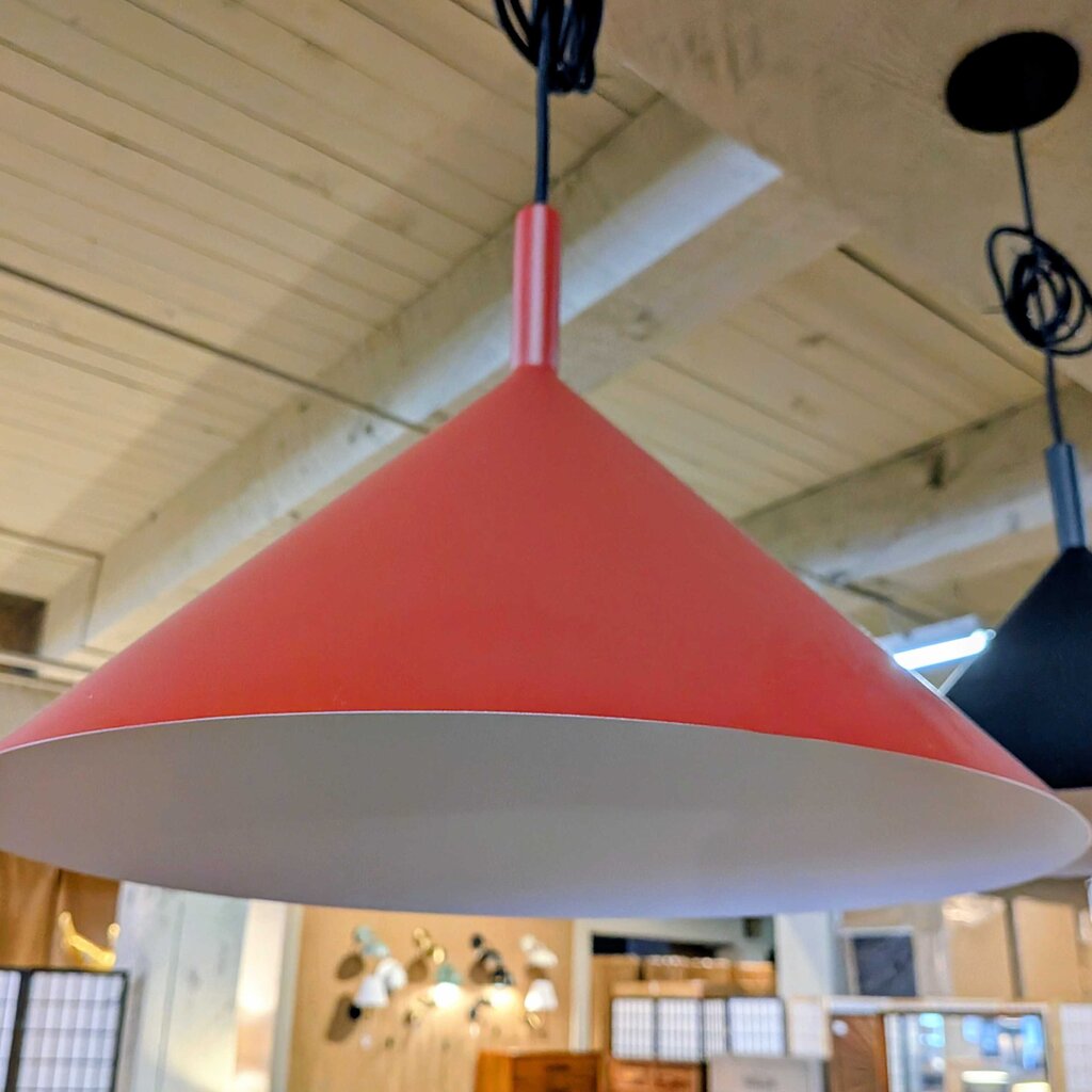 Red pendant light hanging in a room with wooden ceiling