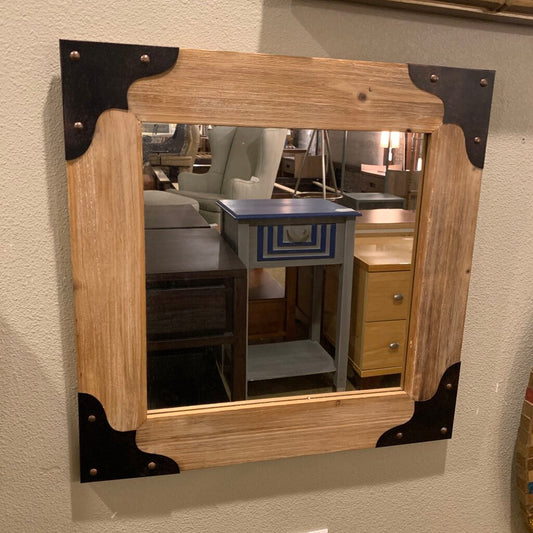 Wooden-framed mirror with metal accents on a wall