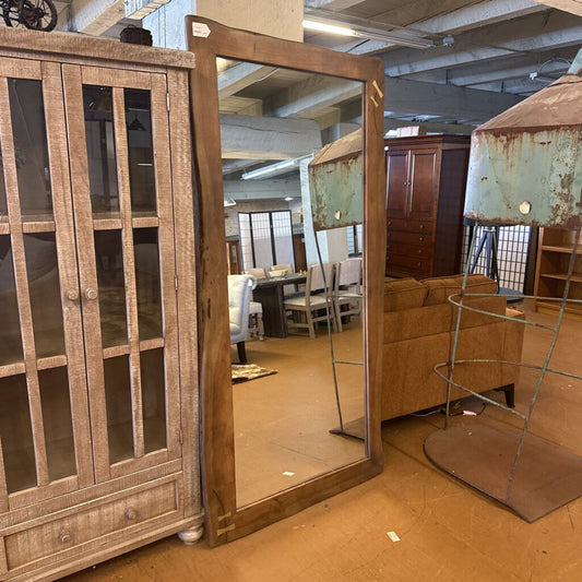 Wooden cabinet with glass doors and a large mirror in a warehouse setting.