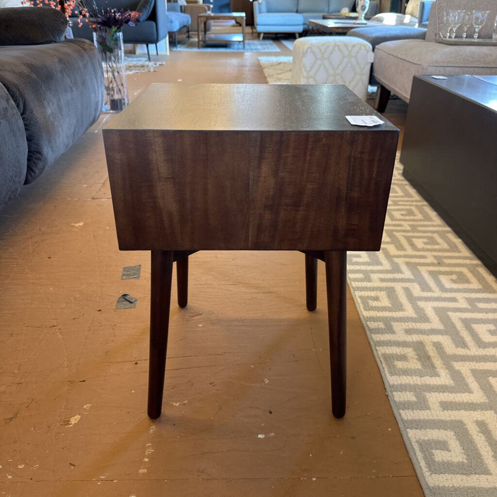 Wooden side table in a living room setting with furniture and decor.
