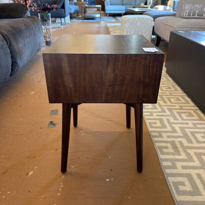 Wooden side table in a living room setting with furniture and decor.