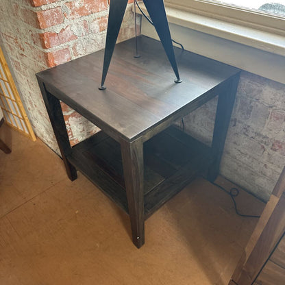 Small wooden table with metal legs against a brick wall.