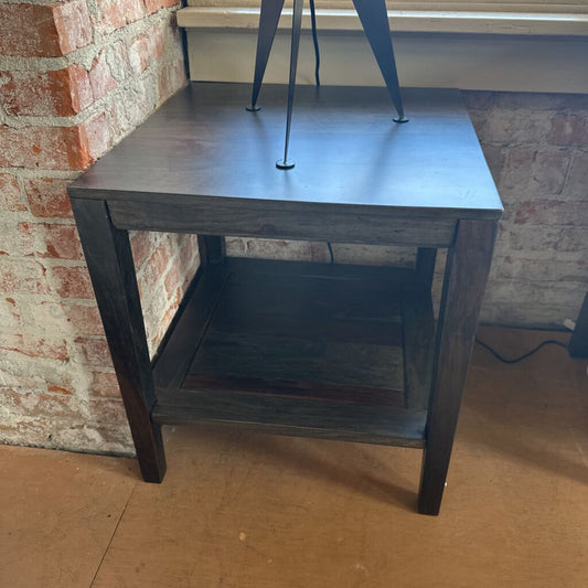 Dark wooden side table against a brick wall.