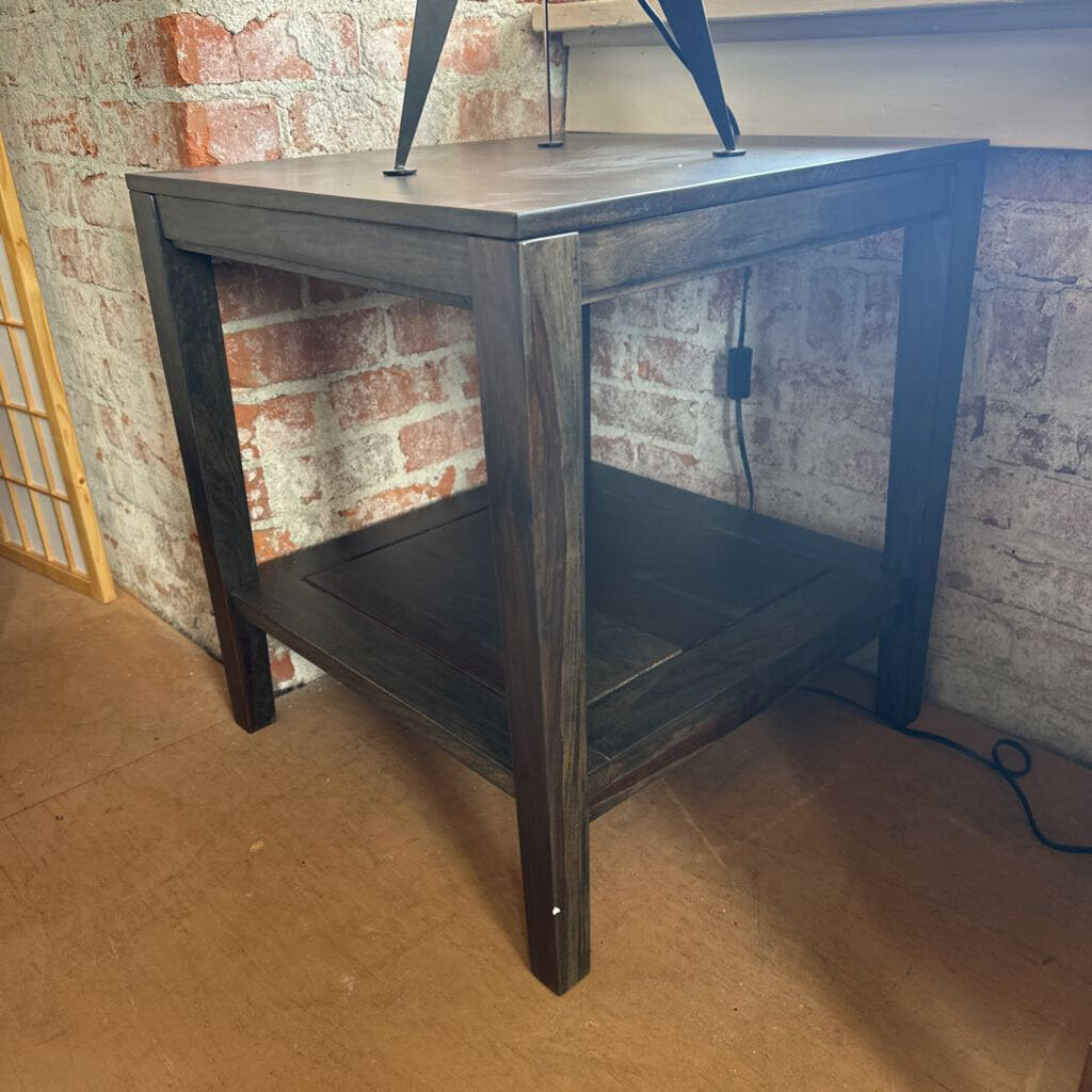 Dark wooden side table against a brick wall.